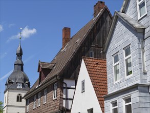 Path next to half-timbered houses and church, striking for its red roofs and historic architecture,