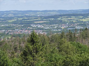 View over a town and surrounding forests and hills under a slightly cloudy sky, Detmold, North