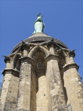 Close-up of a stone statue on a tower in front of a clear blue sky, Detmold, North