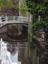 Romantic canal with a white bridge and building reflections in the calm water, Delft, Holland,