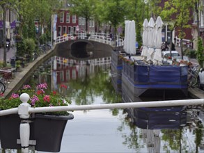 Scenic canal view with blooming flowers, a small bridge and a quiet city atmosphere, Delft,