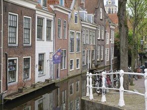 Row of old brick houses and bicycles standing along a canal in a historic town, Delft, Holland,