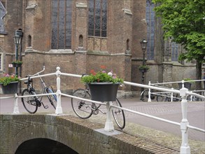 Canal bridge with bicycles and flower pots next to historic brick buildings, Delft, Holland,