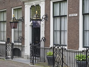 A stylish entrance to a historic city building with ornate lanterns and an iron gate, Delft,