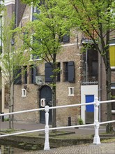 Old brick house with shutters and trees on the canal, Delft, Holland, Netherlands