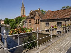 Picturesque bridge with flowers, historic buildings and church tower, sunny summer atmosphere by