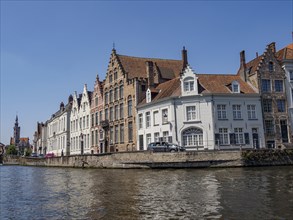 Row of historic buildings along a canal with detailed architecture and clear sky, Bruges, Flanders,