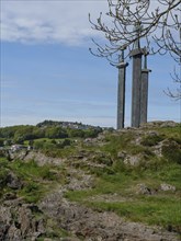 Three monumental statues on a grassy hill under a cloudy sky, ideal for walks, Stavanger, Norway,