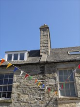 Stone building with colourful flags and a chimney under a clear sky, lerwick, shetlands, scotland,