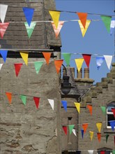 Colourful flags hang between traditional buildings under a bright sky, lerwick, shetlands,