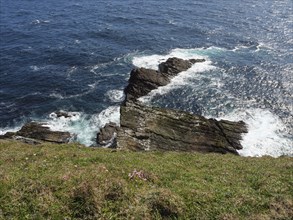 Rocky cliff and waves crashing against the shore in daytime, lerwick, shetlands, scotland, uk