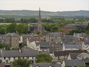 A city view with a church in the centre, surrounded by historic buildings and green landscapes,