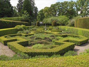 A well-kept garden with a hedge maze and various green plants, sunny day, inverness, scotland,