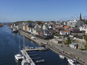 View of a harbour and a promenade with many houses and boats under a clear sky, haugesund, norway,