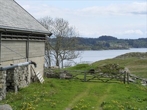 Country house with a view of a lake and green meadow, surrounded by trees and clouds, haugesund,