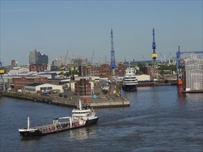 Industrial harbour with several large cranes and ships in the water, urban surroundings in the