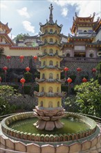 A pagoda in the centre of a water fountain in a temple complex with red lanterns, Pattaya,