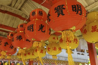 Close-up of several red lanterns with Chinese characters in a traditional temple setting, Pattaya,