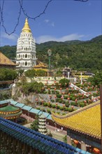 A pagoda in a temple complex with many lanterns and surrounding mountains under a blue sky,