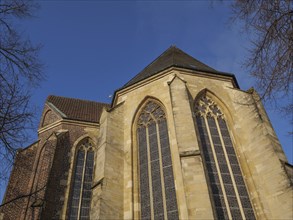 A church with large Gothic windows and a brick faÃ§ade under a clear blue sky, Coesfeld,