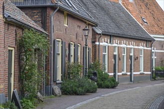 A quiet village street with a row of brick houses, shutters and a traditional lantern, Bredevoort,