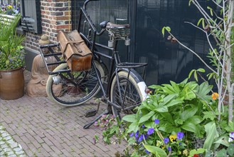 Old bicycle with bags in a cosy alley with many plants and flower pots, Bredevoort, gelderlande,