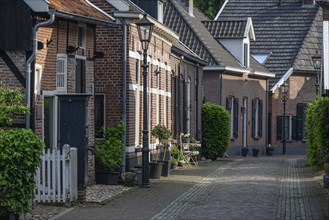 Narrow alley with houses, lanterns and planted pots along the cobblestone alleyway, Bredevoort,