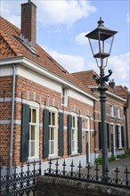 Brick house with shutters and lantern in front of a blue sky with clouds, Bredevoort, Gelderlande,