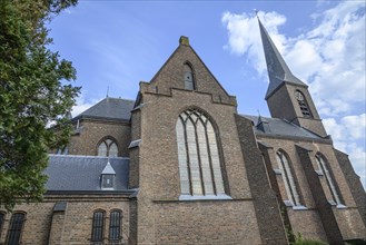 Close-up of a large brick church with magnificent windows under a slightly cloudy sky, Bredevoort,