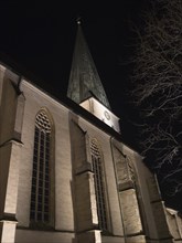 A church tower at night with Gothic architecture and dramatic lighting that emphasises the