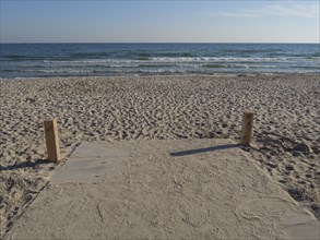 Tranquillity on the beach with sand and sea, framed by wooden posts, under a clear sky, Binz,