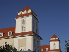 Historic castle building with several towers and red tiled roofs under a blue sky, Binz, Rügen,