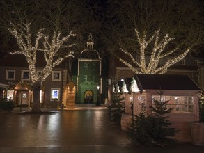 A cosy Christmas market at night, with illuminated trees and historic buildings, Ahaus,