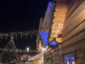 An atmospheric Christmas market at night, with illuminated wooden houses and Christmas decorations,