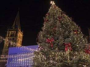 In the centre a large, festively decorated Christmas tree with lights, red bows and a star at the