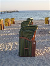 Several green and yellow beach chairs stand on the sandy beach with a view of the calm sea, Binz,