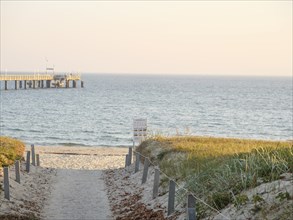 A narrow path leads over the dunes to the calm sea, the jetty is visible in the distance, Binz,