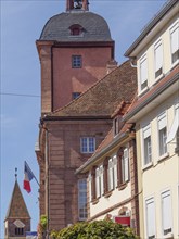 Historic building with a flag and half-timbered houses in the foreground, Wissembourg, Alsace,