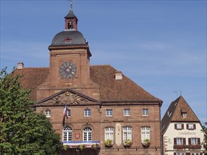 Historic building with clock tower and French flag in a small town with beautiful tiled roofs,