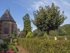 Church with vaulted roof, surrounded by hedges and tree in the front area, quiet garden landscape,