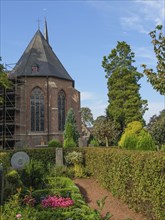 Historic brick church surrounded by manicured hedges and gardens, under a clear sky, marienthal,