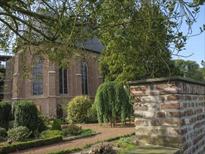 Brick church and garden with hedges and a tree in the foreground, peaceful atmosphere, marienthal,