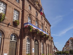 Historic town hall with French flag and flower-decorated windows, in the historic centre of a