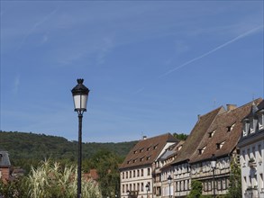 Street lamp in front of a row of traditional houses with green hills in the background,