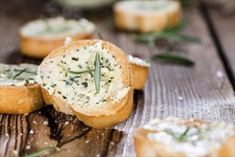 Baguette with Herb Butter and Rosemary on rustic wooden background