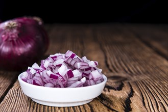 Small bowl with (diced) Red Onions on wooden background