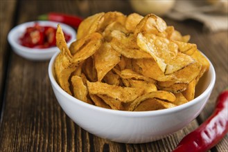 Heap of Chilli Potato Chips (selective focus) on an old wooden table