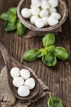 Small Mozzarella balls (on wooden background, selective focus) as close-up shot