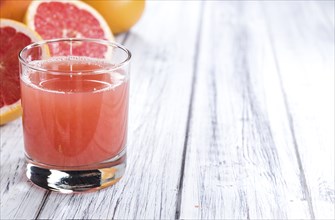 Pure Grapefruit Juice (close-up shot) on rustic wooden background