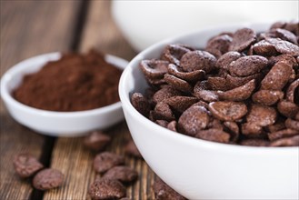 Chocolate cornklakes on wooden background with milk in the background